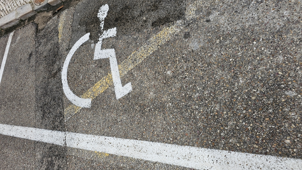 Handicap,parking,symbol,on,worn,asphalt,surface,with,white,and
